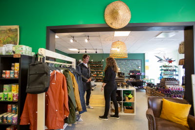 En man får hjälp i att välja jacka i butik