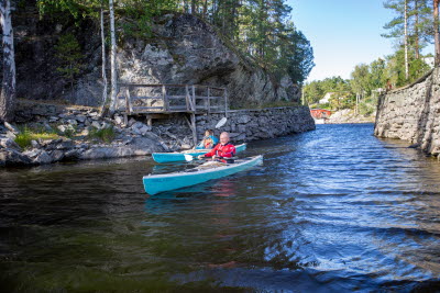En kvinna och en man paddlar kajak i Lennartsfors
